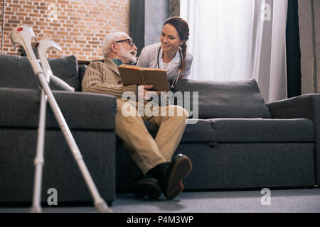 Ältere männliche Patienten mit Buch im Gespräch mit lächelnden Arzt Stockfoto