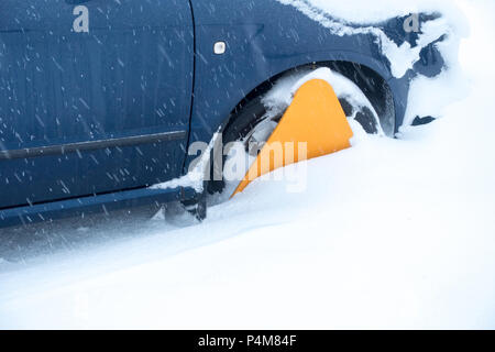 Gelbe rad Klemme auf ein Auto in einem Snow Drift gefangen Stockfoto