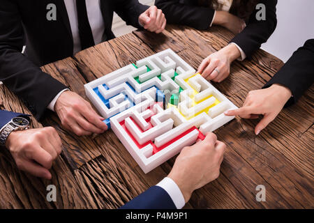 Erhöhten Blick auf Geschäftsleute Hand Lösung Labyrinth zusammen auf Holz- Hintergrund Stockfoto