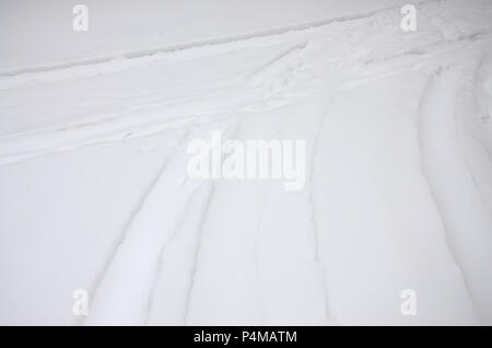 Spuren von den Rädern der Autos auf einer verschneiten Straße. Gefährliche und glatte Drehung des Fahrzeugs. Stockfoto