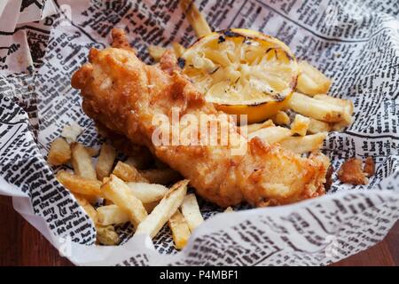 Fisch und Chips mit Zitrone auf Zeitung Stockfoto