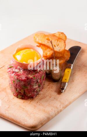 Steak Tartar mit rohem Eigelb und Crostini Stockfoto