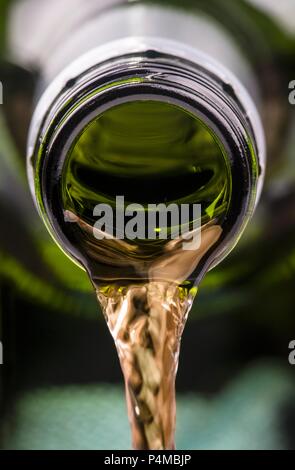Weißwein wird von einer Flasche ausgegossen Stockfoto