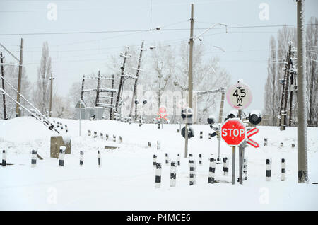 Bahnübergang ohne Barriere mit einer Menge Warnzeichen in den verschneiten Winter. Stockfoto