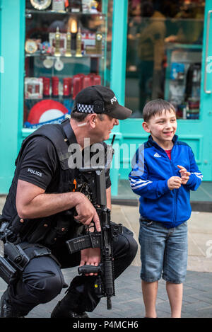 Ein junges Kind Chats und Witze mit einem bewaffneten Polizisten auf der High Street gegenüber von Schloss Windsor in Windsor am Abend vor der königlichen Hochzeit von SKH Prinz Harry und Frau Meghan Markle. Die bewaffneten Polizisten hockte sich auf Höhe des Jungen und lächelte ihn an, während für ein Foto posieren. Stockfoto