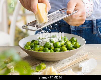 Ein Mann Gitter Käse über den Rosenkohl Stockfoto