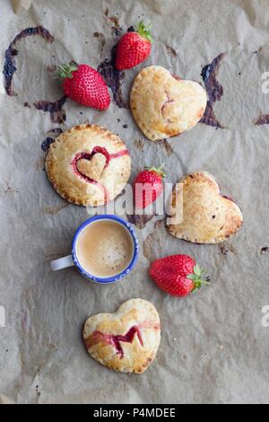 Hand Pies (Pasteten) mit einer Erdbeere füllen und Herzen Dekorationen Stockfoto