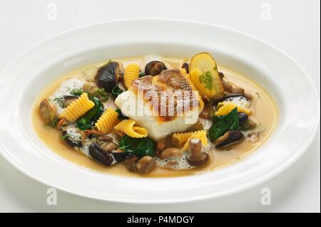 Zanderfilet in einer geräucherten Pilz Bouillon mit Spinat und Baby Gnocchi Stockfoto