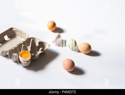 Frische Hühnereier neben einem Ei Box mit einem Gesprungenen open Ei Stockfoto