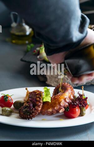 Olivenöl auf Octopus mit Tomaten und Kapern gegossen Stockfoto