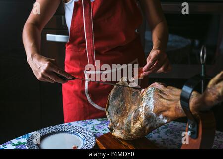 Nicht erkennbare Frau slicing Serrano Schinken Stockfoto