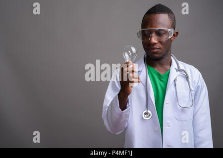 Junge afrikanische Mann Arzt tragen Schutzbrille gegen Grau Stockfoto