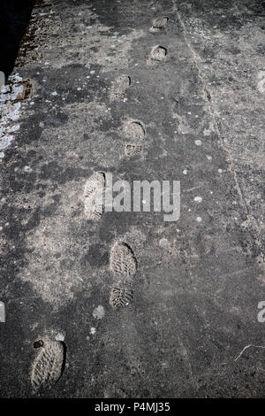 Shoeprints Aufdruck auf dem grauen Asphalt. Stockfoto