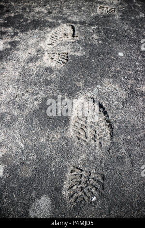 Shoeprints Aufdruck auf dem grauen Asphalt. Stockfoto