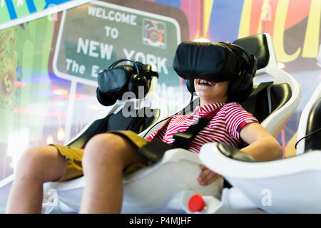 Erstaunt jugendlich Junge schreien, das Tragen von Virtual Reality goggles Filme, Standortwahl in 4D Stuhl. Stockfoto