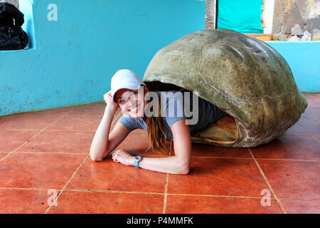 Junge Frau im inneren Leere Galapagos Riesenschildkröte Shell im Heiligtum liegen auf Santa Cruz Island, Galapagos, Ecuador. Stockfoto