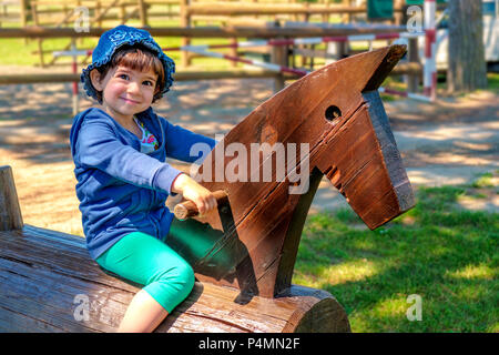 Baby Kind auf hölzernen Pferd in einer Ranch - Lernen zu reiten - Familie Reise nach Reitschule Stall. Stockfoto