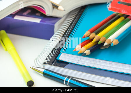 Zurück zu Schule Konzept. Zusammensetzung aus Lieferungen Stapel von Copybooks Bunte Bleistifte Textmarker Gummi Pen geöffneten Arbeitsmappe auf weißen Desktop. Lea Stockfoto