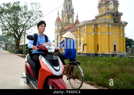 Junger Mann auf seinem Roller vor einer katholischen Kirche in der Nähe des Dorfes Xuan ein, Nam Dinh Provinz, Vietnam Stockfoto