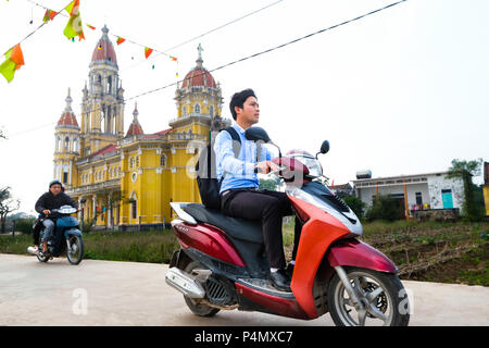 Junger Mann auf seinem Roller vor einer katholischen Kirche in der Nähe des Dorfes Xuan ein, Nam Dinh Provinz, Vietnam Stockfoto