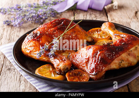 Würzig gegrilltem glasierte Hähnchenschenkel mit Lavendel und Zitrone close-up auf einem Teller auf dem Tisch. Französische Küche. Horizontale Stockfoto
