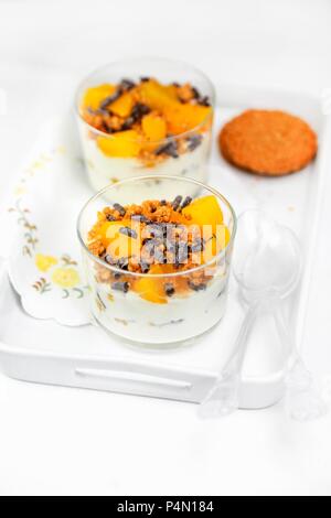 Cremigen Joghurt mit Müsli, Eingemachte Pfirsiche und Schokolade Rollen Stockfoto