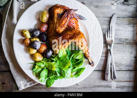 Ein halbes gegrilltes Hühnchen mit gebratenen Kartoffeln und Spinat (von oben gesehen) Stockfoto