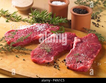 Gewürzt Rindersteaks mit Kräutern und Gewürzen, bereit zu braten. Stockfoto