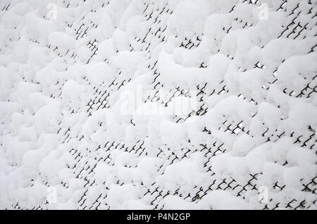 Close-up Metallgitter mit einer dicken Schicht Schnee in den Zellen abgedeckt. Stockfoto