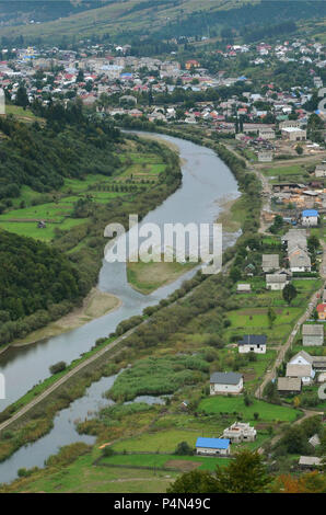 Eine wunderschöne Aussicht auf das Dorf Mezhgorye, Karpaten Region. Eine Menge von Wohngebäuden durch hohe Wald Berge und lange Fluss umgeben Stockfoto