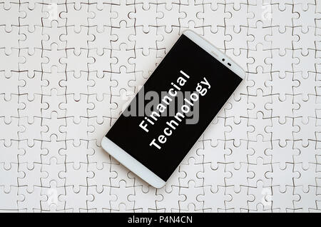 Eine moderne grosse Smartphone mit Touchscreen liegt auf einem weißen Puzzle im zusammengebauten Zustand mit Inschrift. Die Technologie Stockfoto