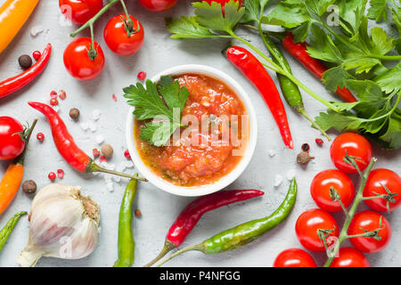 Soße, Ketchup, Lecho in der Platte. Chilli Tomaten Knoblauch und andere Gewürze auf schwarzem Hintergrund Stockfoto