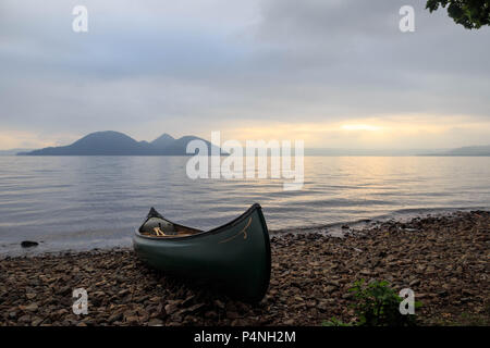 Kanu sitzt am Strand von Crater Lake bei Sonnenuntergang in Hokkaido, Japan Stockfoto