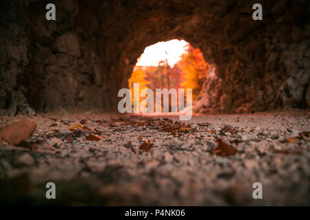Stein gehauenen Tunnel und roten Abendlicht Eröffnung im Herbst Laub Stockfoto