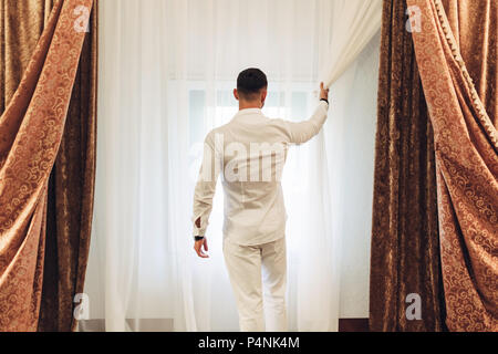 Junger Mann im weissen Anzug im Hotel Zimmer Stockfoto