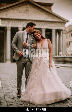 Junge attraktive neu verheirateten Paar und in Rom posiert mit schönen und antike Architektur auf dem Hintergrund am Tag ihrer Hochzeit Stockfoto