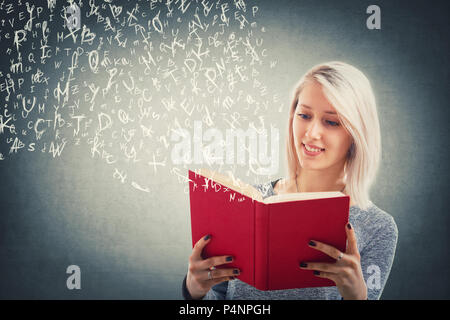 Schöne blonde Mädchen lesen und fliegende Buchstaben des Alphabets Flucht aus dem Roten Buch. Die Magie der Vorlesung. Junge Lehrer studieren, Bildungs- und Stockfoto