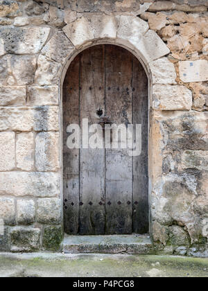 Sehr alten, dunklen geschwungenen hölzernen Tür im alten Kalkstein Mauer des Hauses in Frankreich Stockfoto