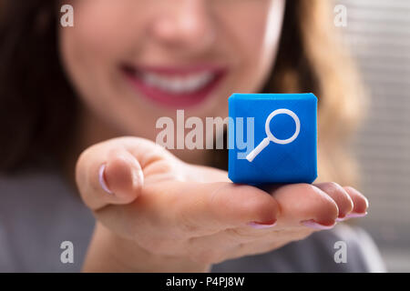 Nahaufnahme der Frau Hand blau Cubic Block mit Lupe Stockfoto