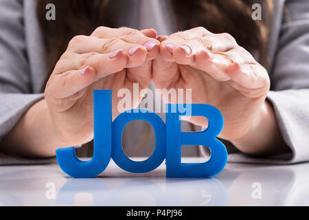 Nahaufnahme von einer Frau, die schützende Hand blau Job Wort Stockfoto