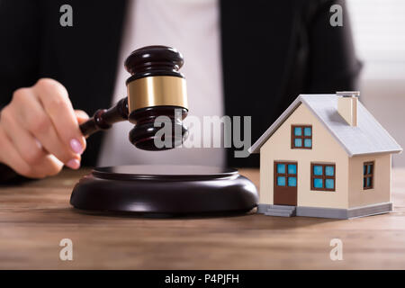 In der Nähe von einem Richter Hand markante Hammer in der Nähe von House Modell über Schreibtisch Stockfoto