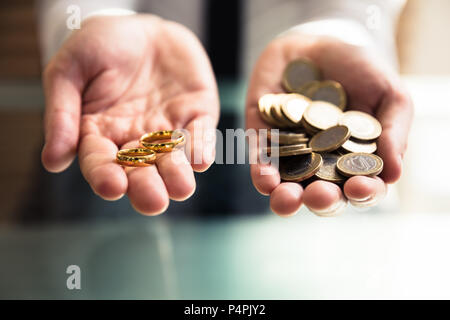 Nahaufnahme von einer Person Hand Hochzeit Ringe und goldenen Münzen Stockfoto