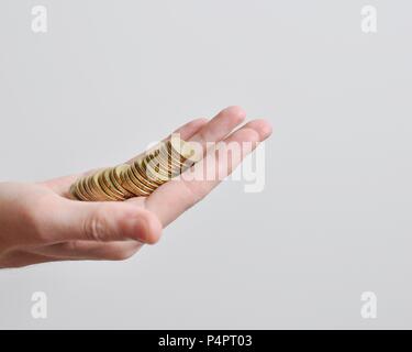 Eine große hand eines Männer Geldhaltung, goldene Münzen, auf weißem Hintergrund, isoliert, Seitenansicht, Kopie Raum Stockfoto