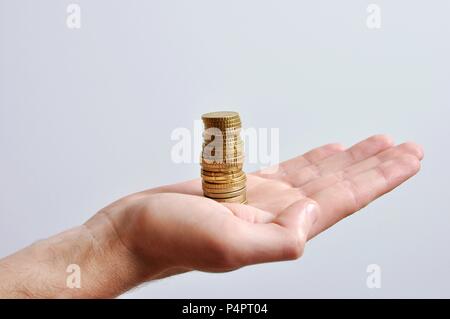 Eine große hand eines Menschen, die eine Geld stack, goldene Münzen, auf weißem Hintergrund, isoliert, Seitenansicht Stockfoto