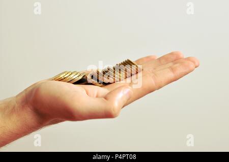 Eine große hand eines Männer goldene Münzen, die in der Palme, auf weißem Hintergrund, isoliert, Seitenansicht, Kopie Raum Stockfoto