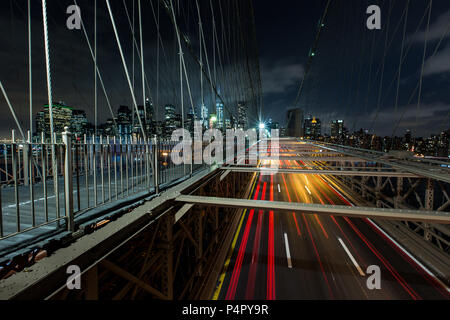 Dämmerung viel Verkehr über die Brooklyn Bridge und Lower Manhattan Skyline, New York, United States Stockfoto