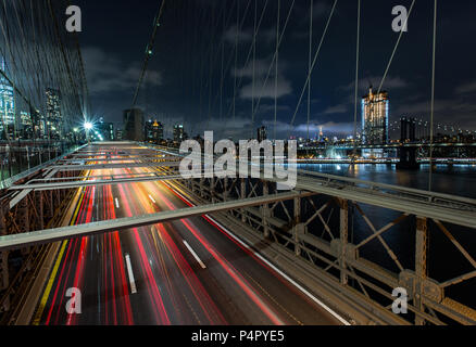 Dämmerung viel Verkehr über die Brooklyn Bridge und Lower Manhattan Skyline, New York, United States Stockfoto