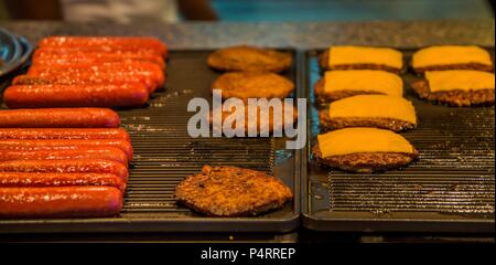 Cheeseburger und Hot Dogs Kochen auf ein heißes Gas Grill Stockfoto