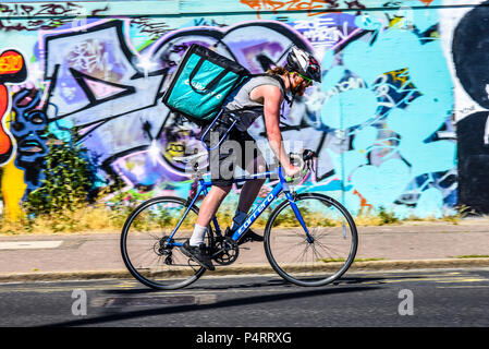 Deliveroo Fahrrad Lieferung rider kämpfen in der Hitze, Reiten Vergangenheit hell Graffiti in Southend On Sea, Essex, Großbritannien. Radfahrer nehmen Essen Lieferung Stockfoto