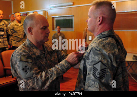 KABUL, Afghanistan - Generalmajor David Hogg, stellvertretender Kommandeur der Armee, NATO Training Mission in Afghanistan, stellt eine gemeinsame Serviceleistung Medaille zu Master Sergeant John Wood für Distinguished Service und als Teil der unbesungenen Helden Programm vor einer Masse von United States Flieger bei der kombinierten Air Power Übergang Kraft Conference Center auf der Afghan National Army Air Corps Base in Kabul, Afghanistan am 16. April 2010. (US Navy Stockfoto